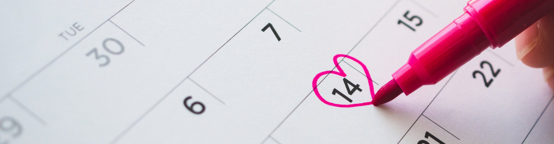 Female Hand with pen mark heart shape on calendar date at 14th valentine day